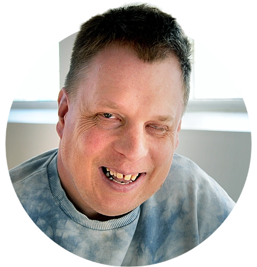 Porträtt av Kristian, han ler mot kameran.